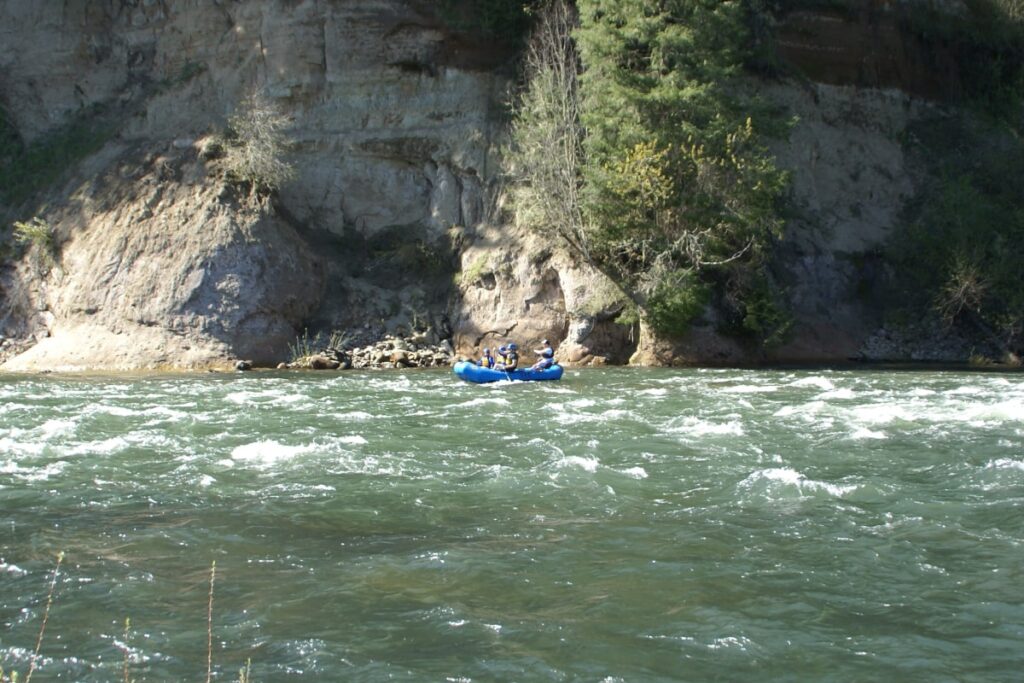A wide shot of guided river rafters navigating mild white water on the Clackamas River.