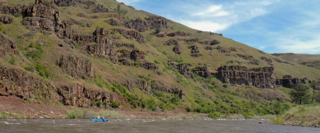 Catarafts and Rafts in a wide shot of Canyons and rock formations along the Grande Ronde River.