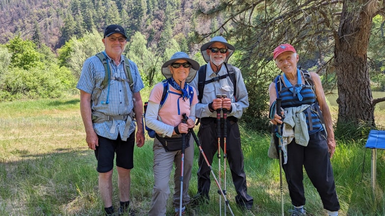 A group of four elderly hikers smile and take a break in an Oregon Forest.