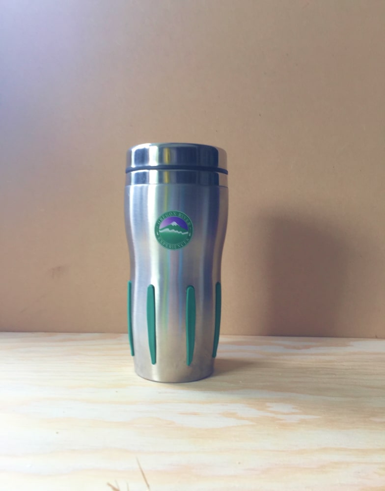 A silver or chrome thermos with green hand grips featuring a lid and Oregon River Experiences logo.