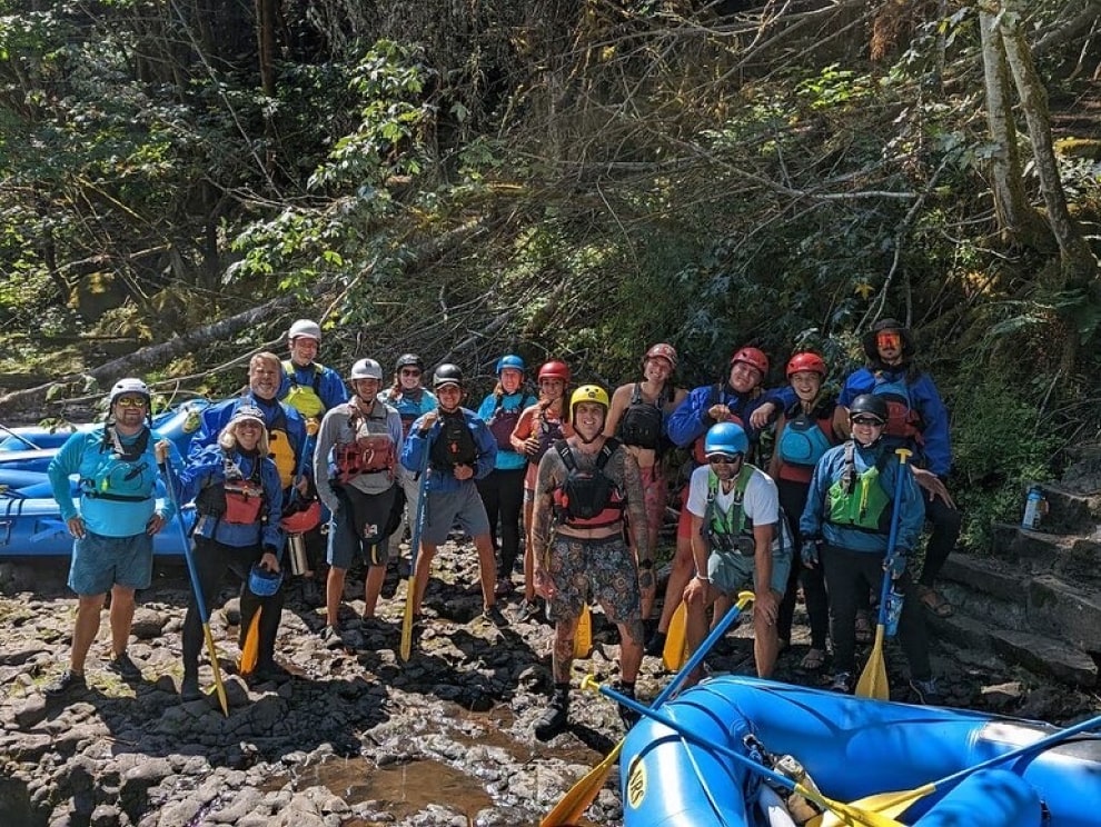 A group of River Guides and employees for Oregon River Experiences take a group photo along the river.