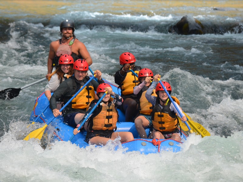 A guided group of seven white water rafters navigate white waters rapids along an Oregon river.