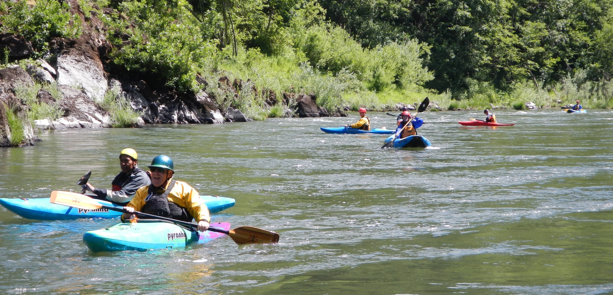 Seven different kayakers navigating the Rogue River in Oregon.